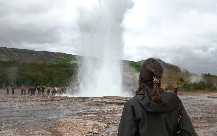 A visitor watching Strokkur geyser erupt at Haukadalur