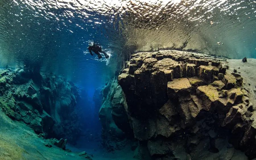 A snorkeller above the basalt walls of the Silfra fissure